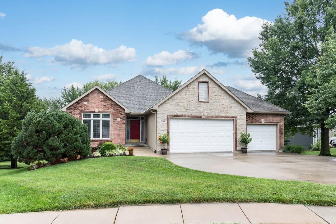 Brick and stone single-family home with two-car garage and manicured lawn