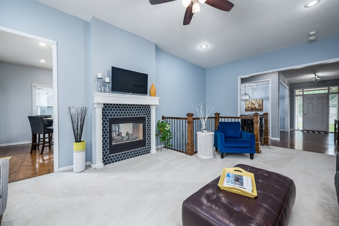 Modern blue living room with fireplace, TV, blue armchair, and dark leather ottoman