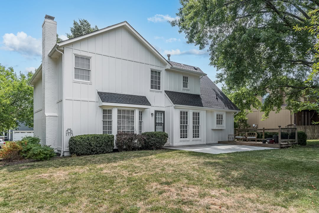 White two-story house with dark roof, front porch, and manicured landscaping